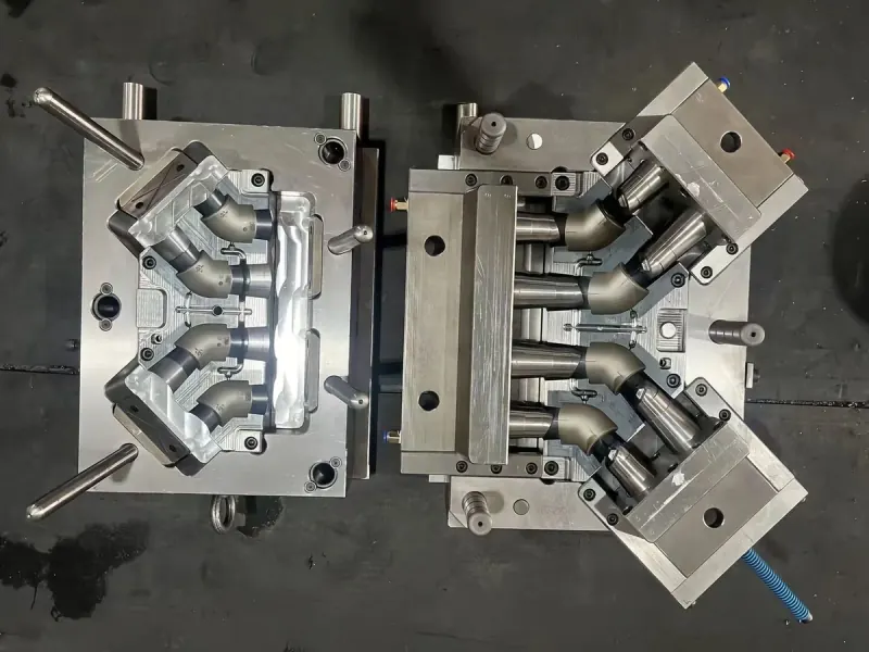 Open four-cavity elbow fitting mold showing the core and cavity arrangement