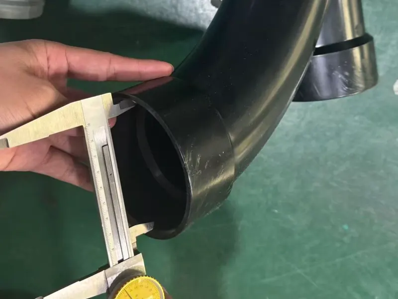 Black curved pipe fitting during a physical check with a caliper